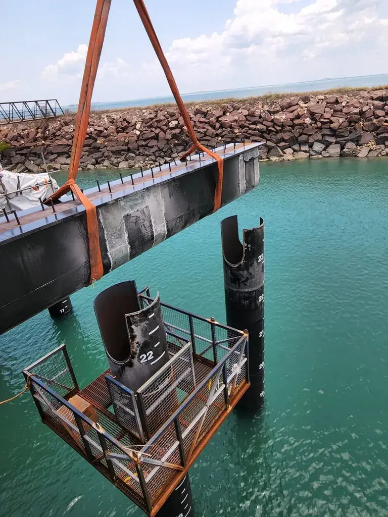 Crane lifting a steel beam on a marine waterfront